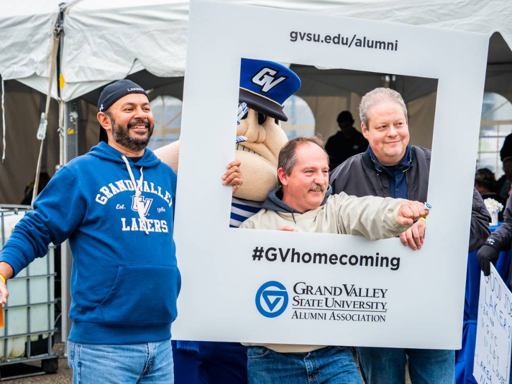 3 alumni pose with Louie and the #GVhomecoming sign